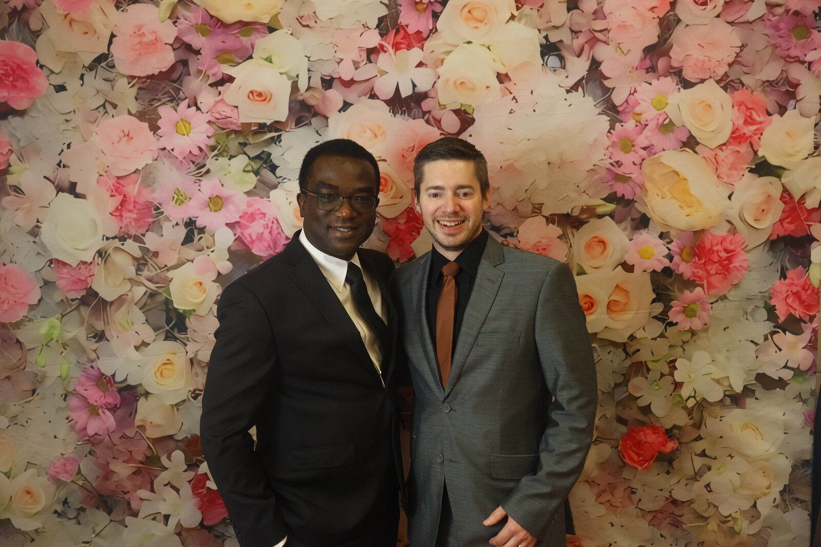 Calgary wedding guests in suits at the floral photo booth backdrop